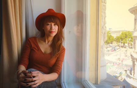 mage of asian woman looking through window, happy asian woman enjoying vacationの写真素材