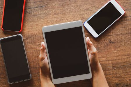 Small hands of a boy holding tablet  on wooden table at homeの写真素材
