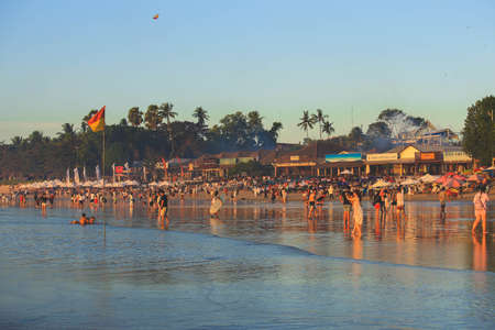 Jimbaran, Bali, Indonesia - August 10, 2019: Tourists enjoy their holiday on Jimbaran beach with seafood restaurants on the backのeditorial素材