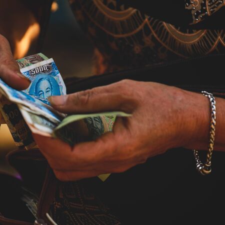 Selective focus on dong banknote on Vietnamese woman's handsの写真素材
