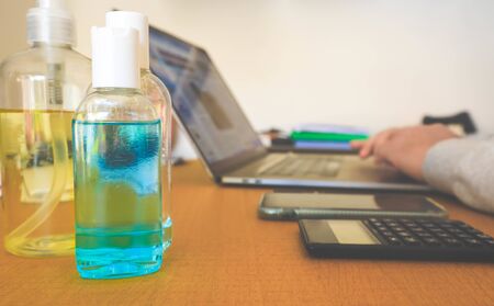 Blue bottles of hand sanitiser on a table during work from home to protect against coronavirus disease or covid-19.の写真素材