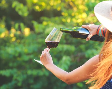 Glass and bottle of red wine in selective focus on glass of wine. pouring red wine at vineyardの写真素材