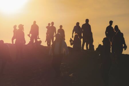 Blurred background people walking on sand dunes beach during the sunsetの写真素材
