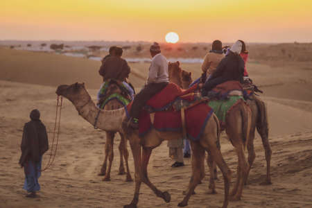 Tourists riding camel on Thar desert in Jaisalmer during the sunset, India. Thar Desert is a large arid region in the northwestern part of the Indian.のeditorial素材