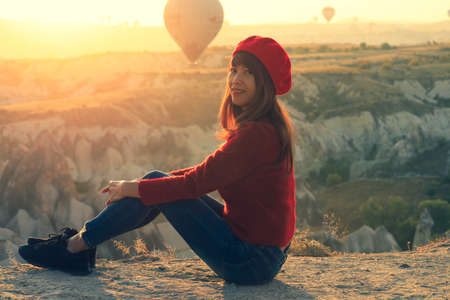 Soft focus on asian woman sitting on fantastic landscape with hot air ballons in early moning at Cappadocia, Turkyの写真素材