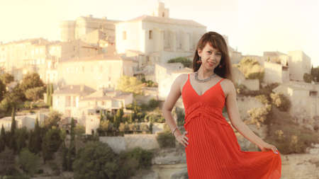 Beautiful asain woman in red dress with Gordes village as background, one of the most beautiful villages in Franceの写真素材