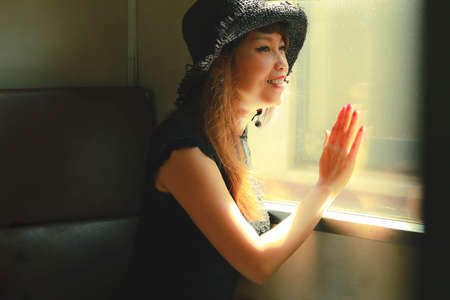 Smiling asian woman looking through old retro train window, traveling conceptの写真素材