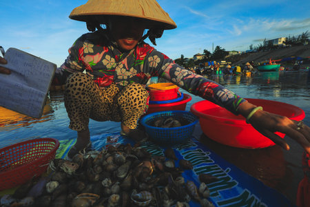 Mui ne - Vietnam - January 22, 2019: Local vendor is collecting fishes and shelles at famous fishing village in Mui ne, Vietnamのeditorial素材