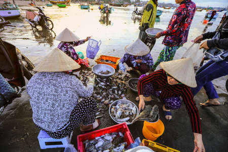 Mui ne - Vietnam - January 22, 2019: Local vendor is collecting fishes and shelles at famous fishing...