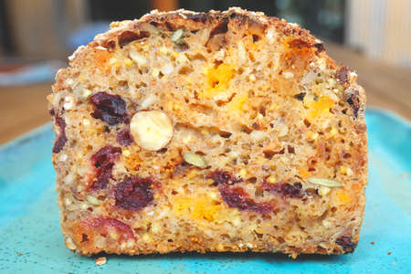 A piece of bread with dried fruits on blue plate, dried apricots, raisins, prunes and hazelnuts, top view.の写真素材