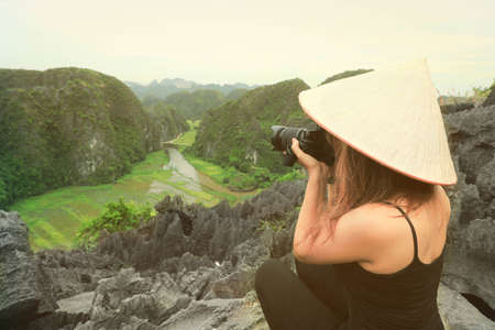 Photographer asian woman holding slr camera professional photography in Ninh Binh, Vietnamの写真素材