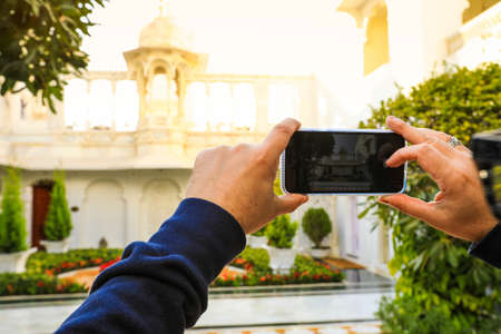 Selective focus on moblie phone taking picture of traditinal building in India