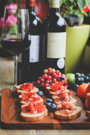 Selective foucs on ham jamon serrano on bread and glass of red wine on wooden tableの写真素材