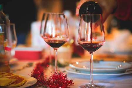 Hand poring red wine on Christmas dinner tableの写真素材