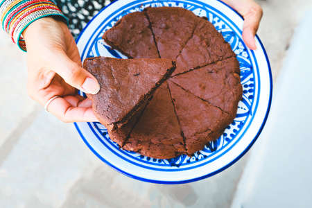 Hands holding a plate with chocolate cakeの写真素材