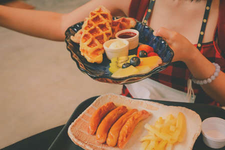 Woman hand holding a plate of fresh fruit, a scoop of ice cream and waffleの写真素材