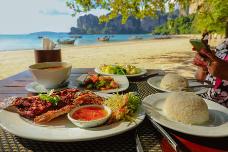 Fried fish and Thai food on table on the beach at Railay beach, Krabi, Thailand, healthy eating conceptの写真素材