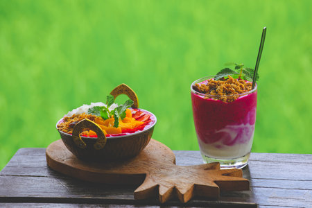 Dragon fruit smoothie in the glass and in brass bowl on table in tropical cafe outdoorの写真素材