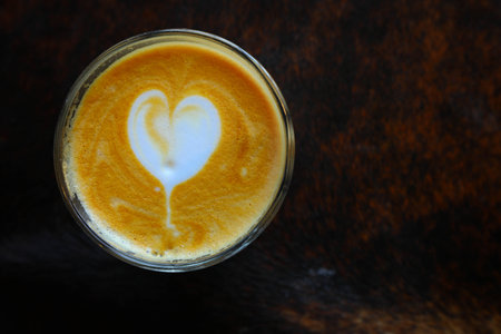 a cup of coffee with foam on wooden table, top viewの写真素材