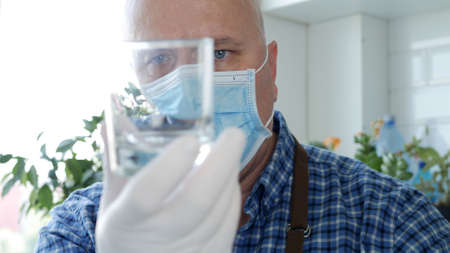 Bartender Wearing a Face Mask and Gloves in His Hands Washes and Cleans an Empty Glassの写真素材