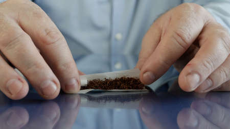 Smoker Roll a Handmade Cigarette Using Cigarette Paper a Filter and Tobaccoの写真素材