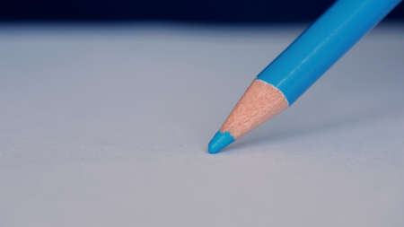 Image with a Person Drawing with a Colored Pencil on a White Piece of Paper
