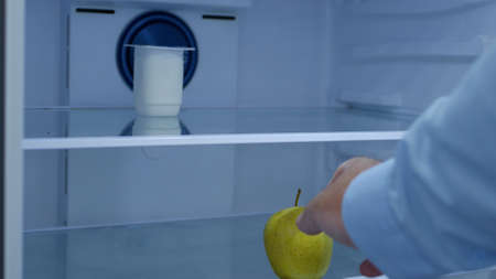 Hungry Man Opens the Empty Fridge Looking for Food and Take an Appleの写真素材