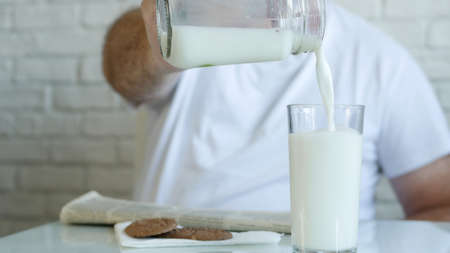 One Person Read a Newspaper and Fill a Glass with Fresh Milk for Breakfast, Enjoying a Tasty and Full with Vitamins Drinkの写真素材
