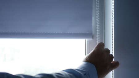 Businessman in Office Room Opening Interior Vertical Blinds from the Windowの写真素材