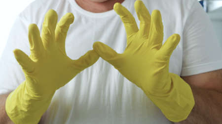 Closeup Image with a Person Hands Wearing Protective Yellow Household Gloves Used in the Kitchen Cleanseの写真素材