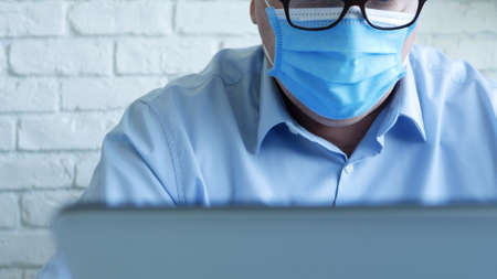 Doctor in a Hospital Office with a Face Mask and Protective Gloves Using a Laptopの写真素材