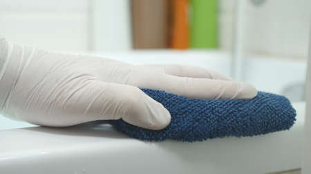 Nurse's Hand Cleaning the Bathtub Surface with a Dry Towelの写真素材