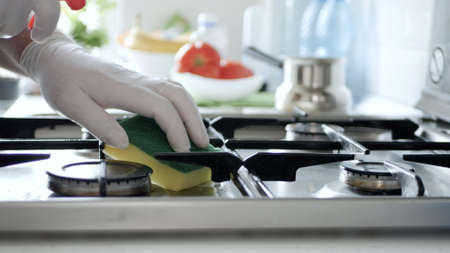 Busy Person in the Kitchen Wearing Gloves Cleans with Solution the Cooker Stove.の写真素材