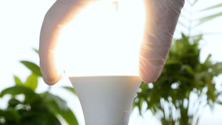 Electrician's Hand Rotates a Led Bulb in Electrical Socket Turning On the Light