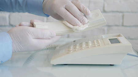 Image with Hands Wearing Protective Gloves Cleaning with a Clean Wipe and Medical Disinfectant a Telephoneの写真素材