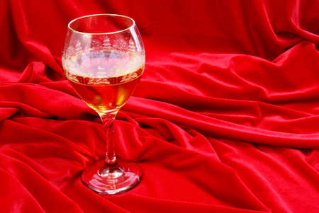 Golden wine in glass on red velvetの写真素材