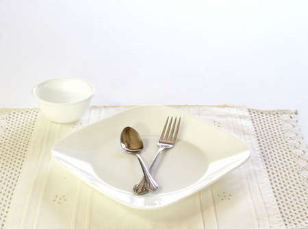 Table setting with white plate and bowl, spoon and fork.の写真素材