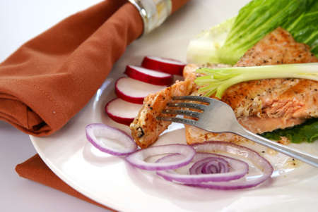 Cooked pink salmon with lettuce leaf, onions, and radish.