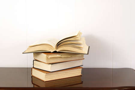 Old hardback books on polished dark cherry wood tableの写真素材