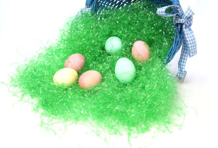 Pastel colored easter eggs and green grass spilling out of a country blue colored easter basket.