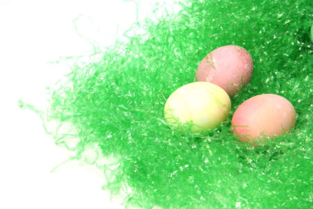 Three pastel colored easter eggs on green easter grass with white copyspace to the side.