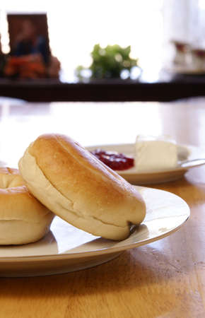 Breakfast of plain bagels with coffee, cream cheese, and strawberry preserves.の写真素材