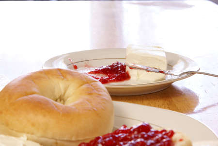 Cream cheese and strawberry preserves with fancy butter knife. Plain bagel blurred in the foreground.の写真素材