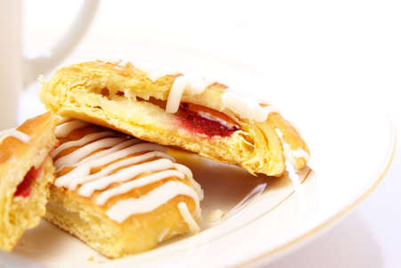 Danish pastry with strawberry and cream cheese filling, on plate next to cup of cappuccino. High...