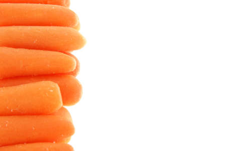 Baby carrots lined up along the side of a white background to create a border, frame or backgroundの写真素材