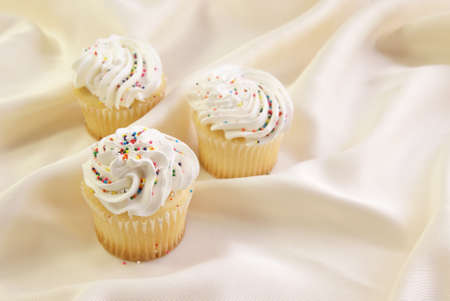 Festive cupcakes with whipped cream icing and candy sprinkles.の写真素材