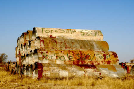 Metal For Sale. Large corrugated metal sheets laying in field. For sale written on the side.の写真素材