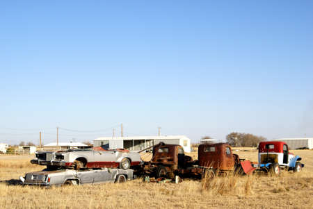Old rusted trucks and cars sitting in a field under a deep blue skyの写真素材