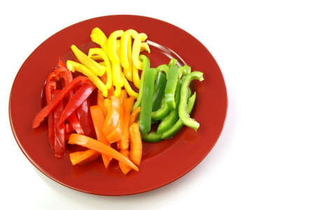Bell pepper strips in red, orange, green and yellow on a red plateの写真素材