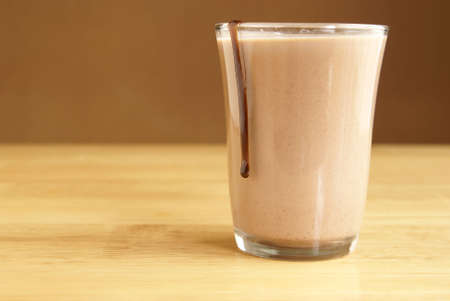 Drip of chocolate sauce running down the outside of a glass of chocolate milkの写真素材